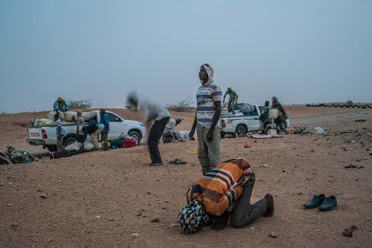 Men pray before they start the treacherous journey across the desert from the Agadez to Libya. Image by Nichole Sobecki. Niger, 2017.