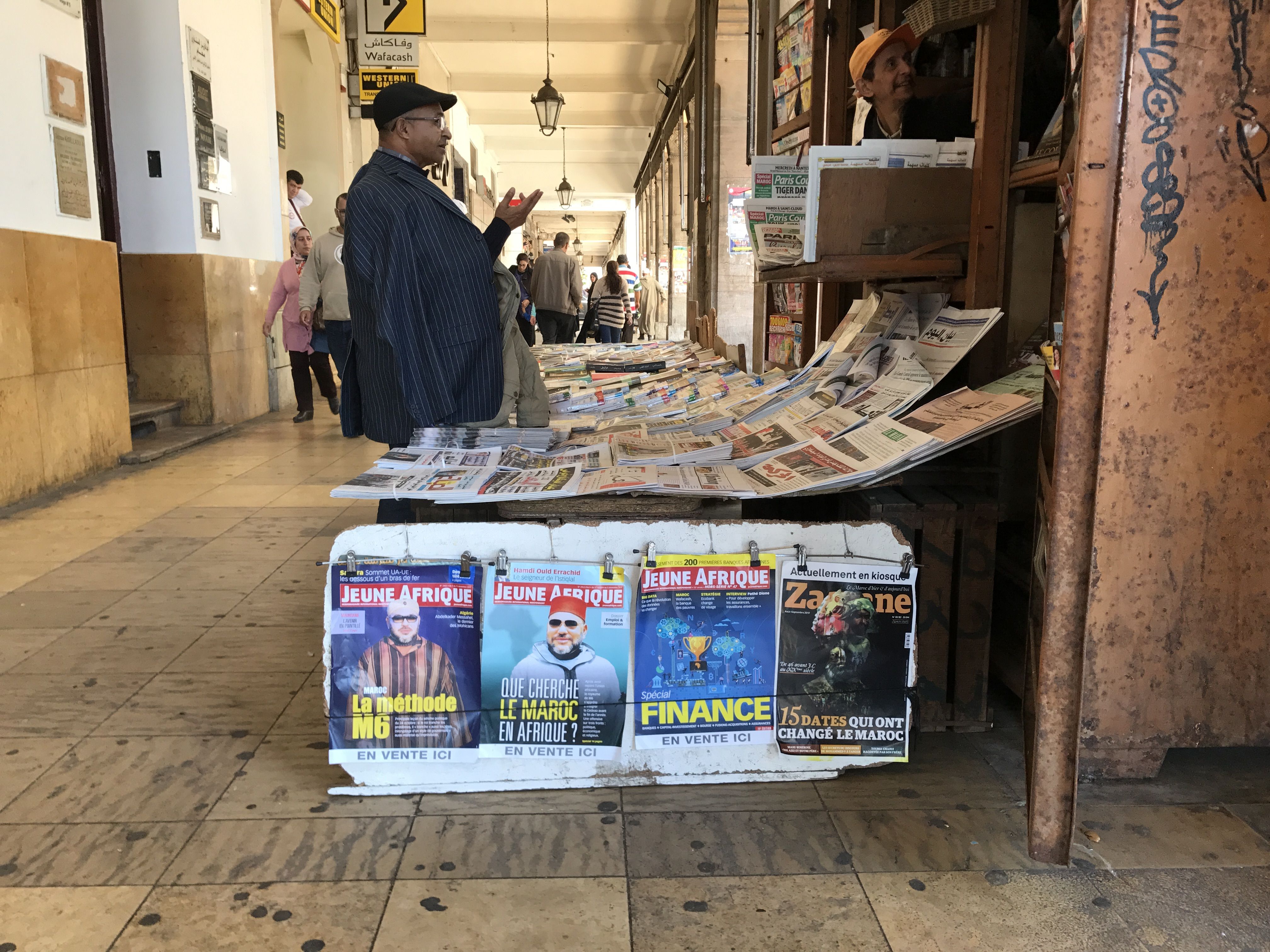 A customer talks to the vendor of a newsstand in Morocco’s capital. Very few publications in Morocco offer critical reporting of the government or the royal family, which uses a system of economic oppression to control what is published. Image by Jackie Spinner. Morocco, 2017.