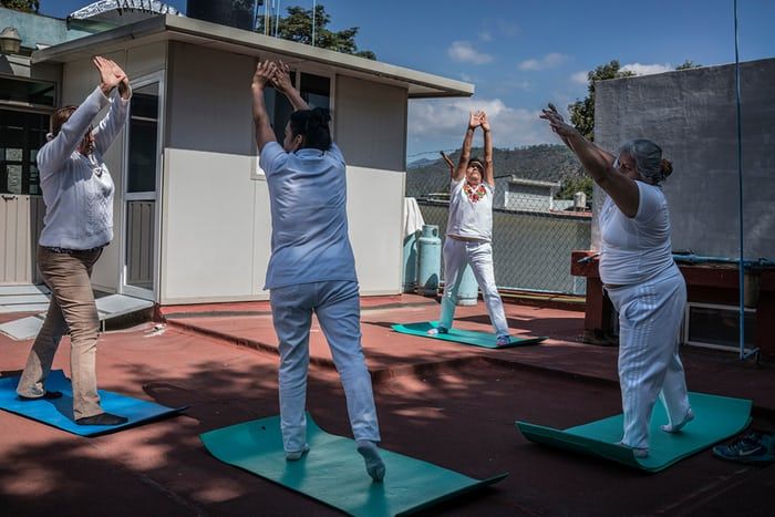 Antonieta Battista Cruz (facing the camera) leads a yoga class as part of a free community programme to combat obesity in Oaxaca. Exercise plans come with advice on healthy diets. Several participants revealed they had been diagnosed with high blood sugar or diabetes and were determined to improve their health for the sake of their families. Image by James Whitlow Delano. Mexico, 2017.