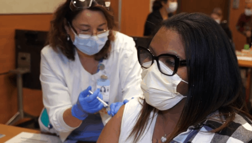 Tanara Gilbert, part of the Environmental Services team at UNC Rex Hospital receives the COVID vaccine during the initial rollout in December, 2020. Image courtesy of UNC Health. United States, 2020.
