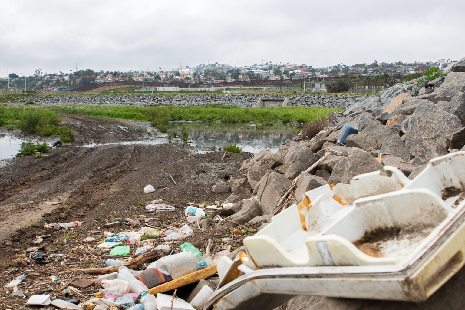 Trash is piled near the U.S.-Mexico border, where sewage from Tijuana flows through. Image by Adriana Heldiz / Voice of San Diego.