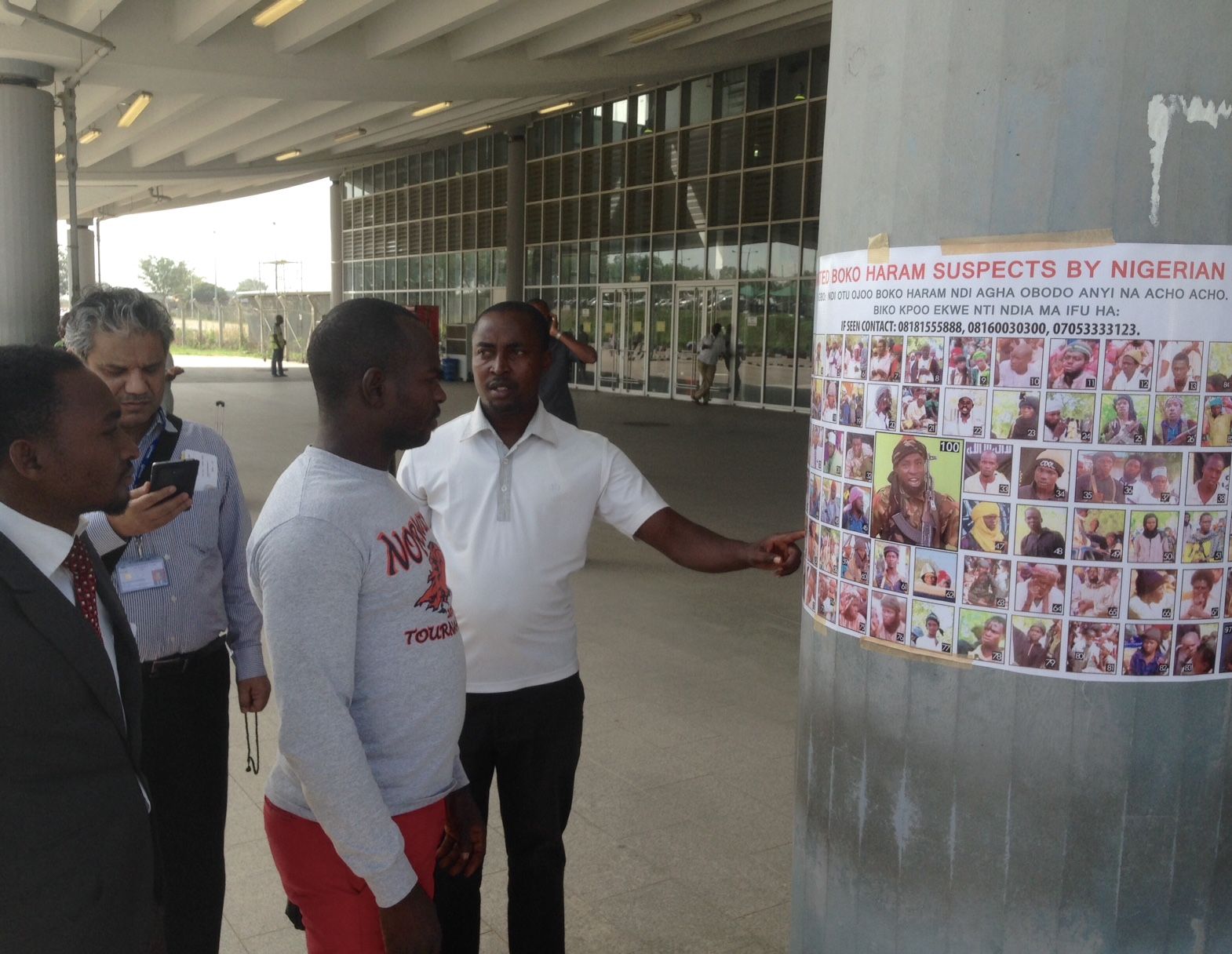 Travelers examine a most wanted poster featuring Boko Haram suspects at an airport near the Nigerian capital. Image by Jason Motlagh. November 2015.