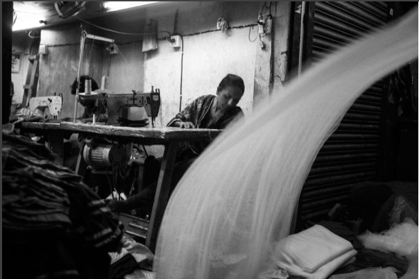 A garment worker in Dhaka, Bangladesh. The small informal factories mostly work for local production, but take subcontracted work for larger, export oriented factories. Image by Jost Franko. Bangladesh, 2016.