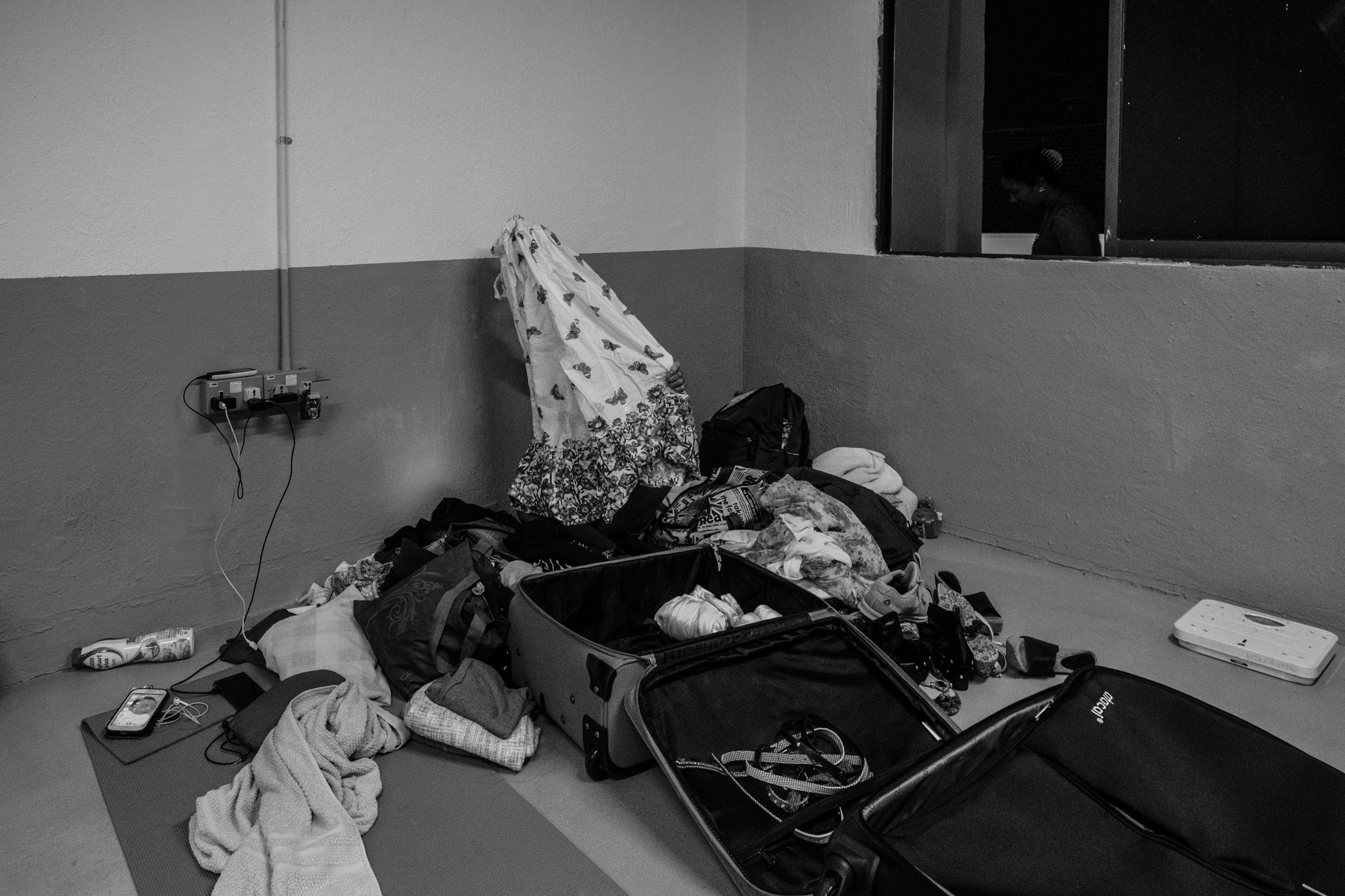 A runaway domestic worker packed her bags inside the shelter. She is finally returning home after months of waiting. Image by Xyza Bacani. Singapore, 2016.