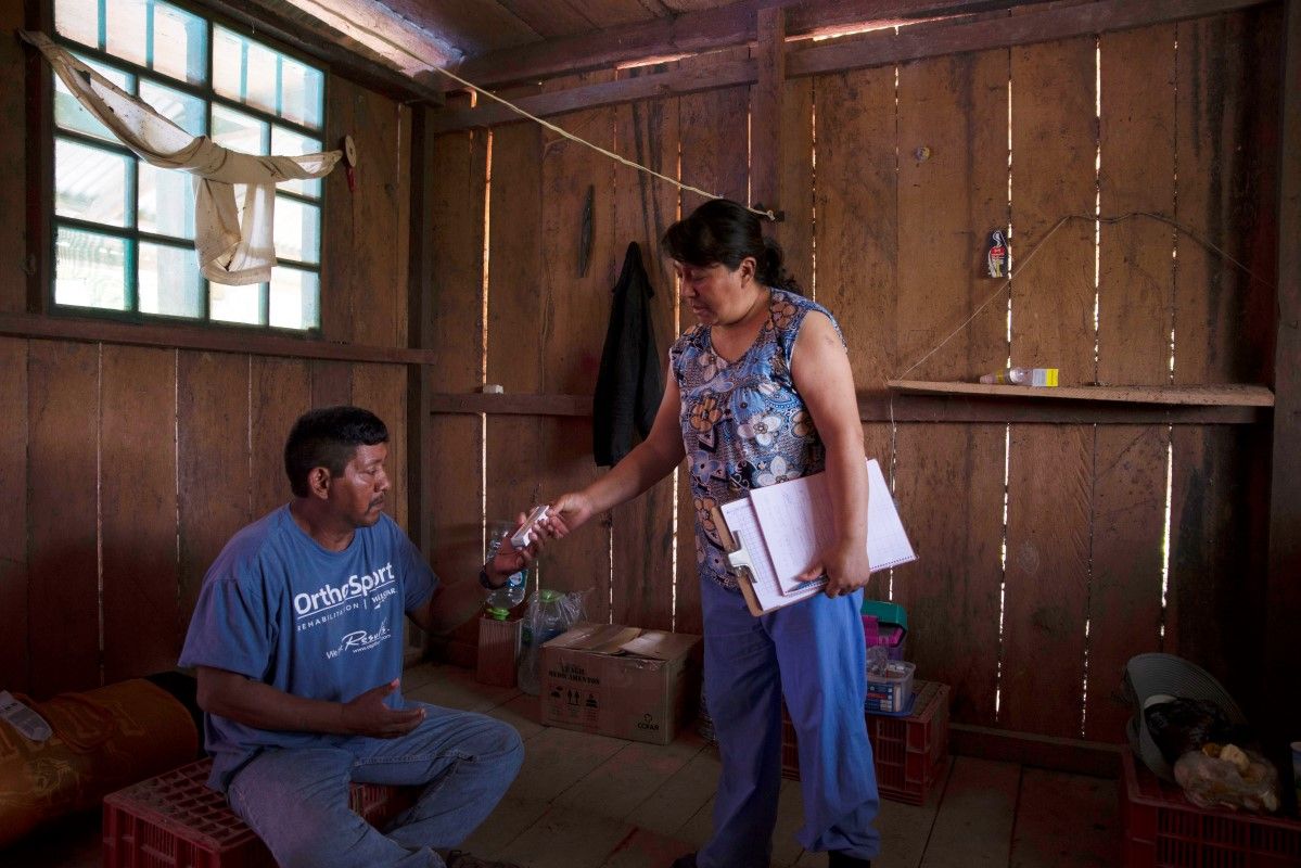 Gimena Gutierrez, a doctor, has health responsibilities in the Yuqui community. Here she gives medicine to former village leader Jhonathan Isategua. Image by Sara Aliaga. Bolivia, 2020.