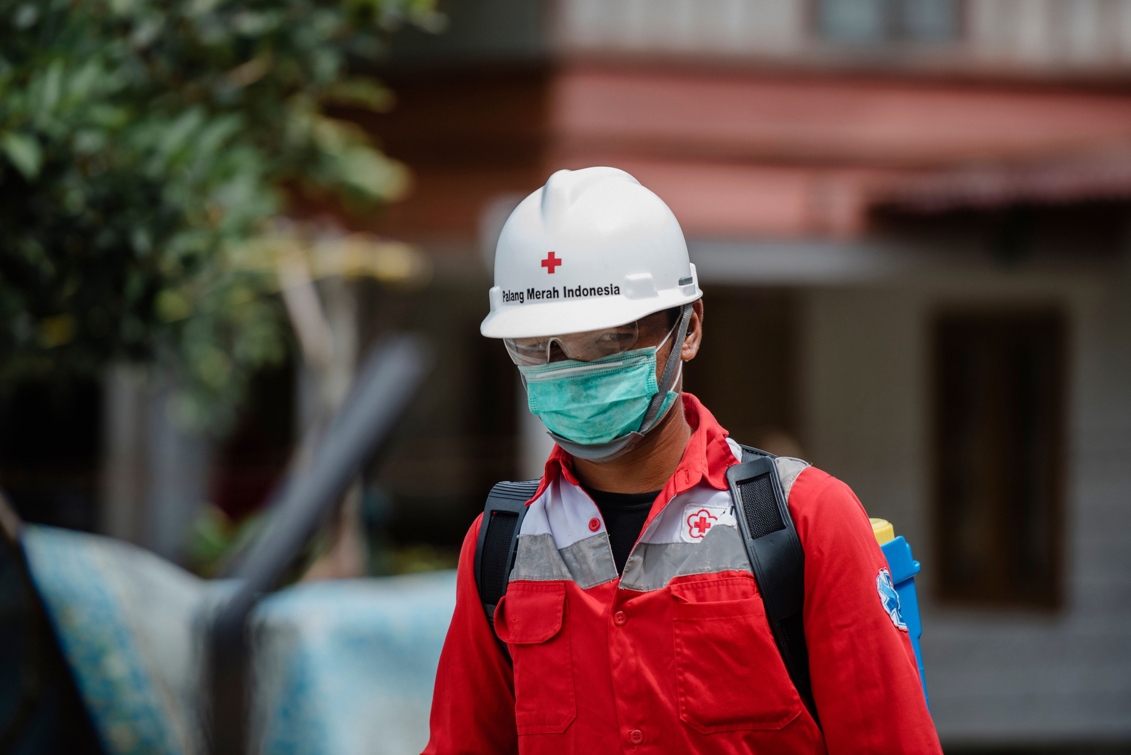 A Red Cross volunteer working to prevent the spread of COVID-19. Image by rizaazhari/shutterstock. Indonesia, 2020. 
