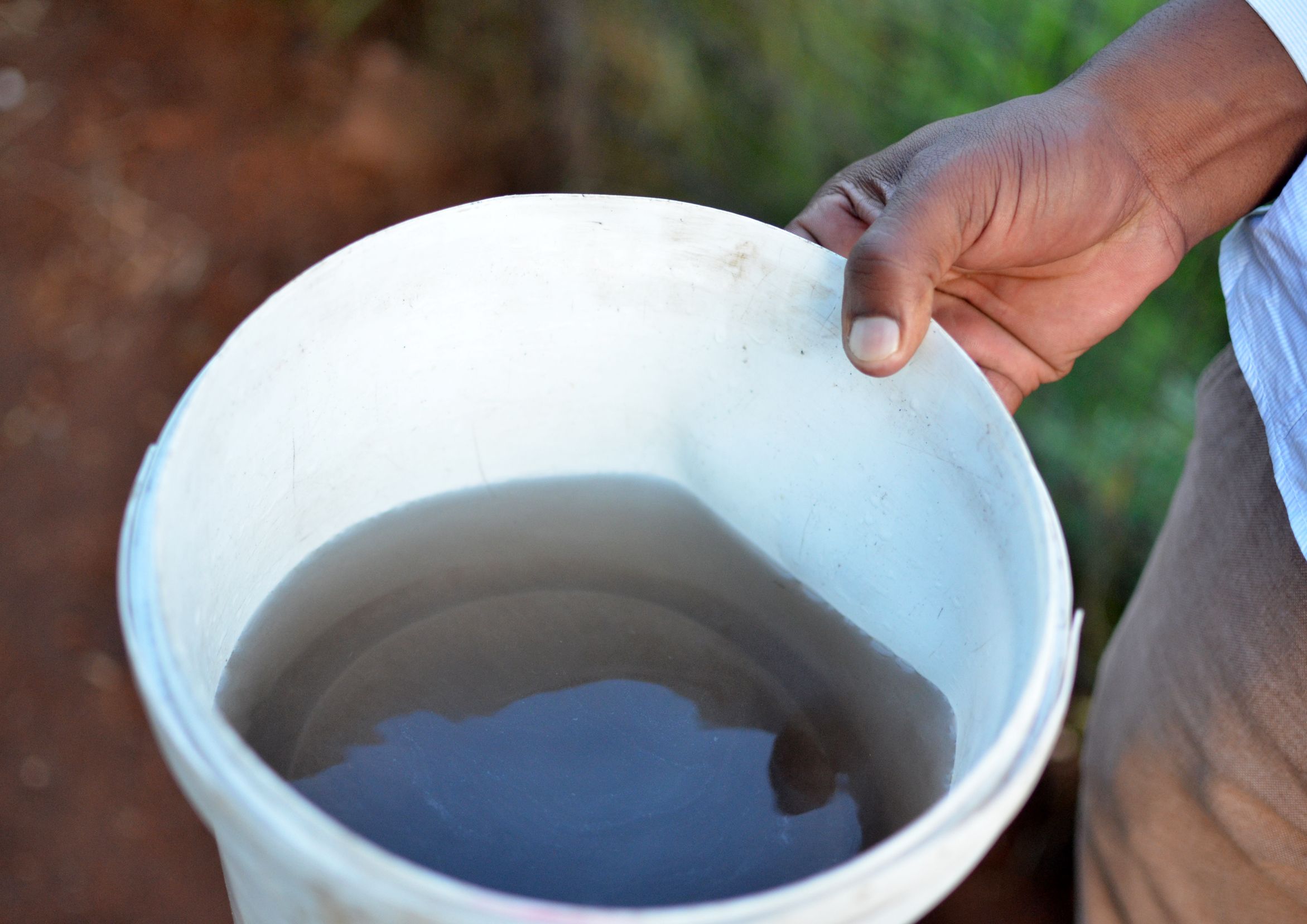 An environmental activist displays a bucket of drinking water turned black from coal dust. Image by Mark Olalde. South Africa, 2017.