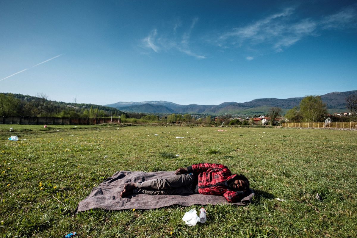 Bihać, Bosnia-Herzegovina: A young Pakistani is seen sleeping rought on the grass of the football pitch in Bihac. Bihac and the north-western part of the country is taking the brunt of the escalating crisis. Being in proximity of the border with Croatia it is a logical route for the people on the move. Image by Ziyah Gafic. Bosnia-Herzegovina, 2020.
