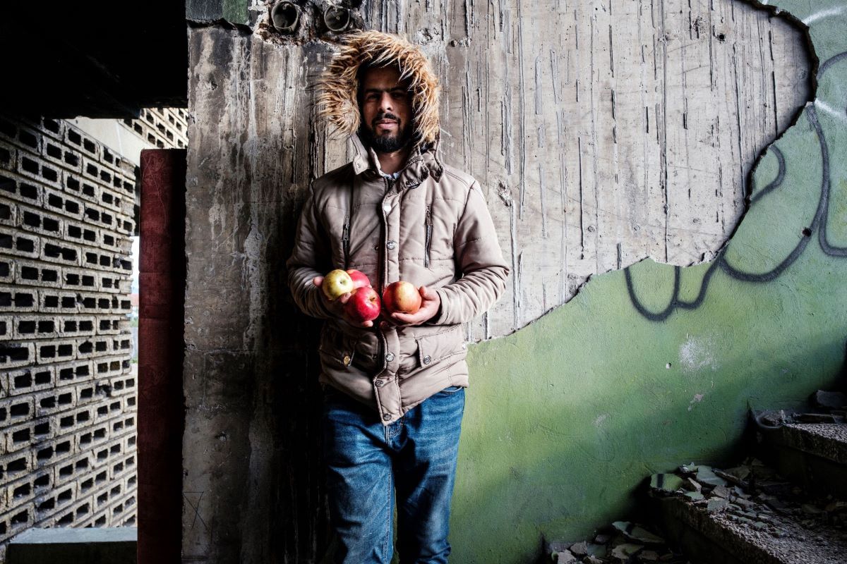 Sarajevo, Bosnia-Herzegovina: Rashid is seen hodling apples brought by the activists Given the largely indolent, inadequate and passive approach of the State people on the move largely depend on the help provided by individuals such as Azra and international organizations such as IOM, UNHCR, DRC, RED CROSS and others. Rashid lives in an abandoned, derelict building of the retirement home. The building was on the frontline during the war in the 90’s and it is completely destroyed. It lacks all the basic necessities such as electricity, heating and running water. Image by Ziyah Gafic. Bosnia-Herzegovina, 2020.
