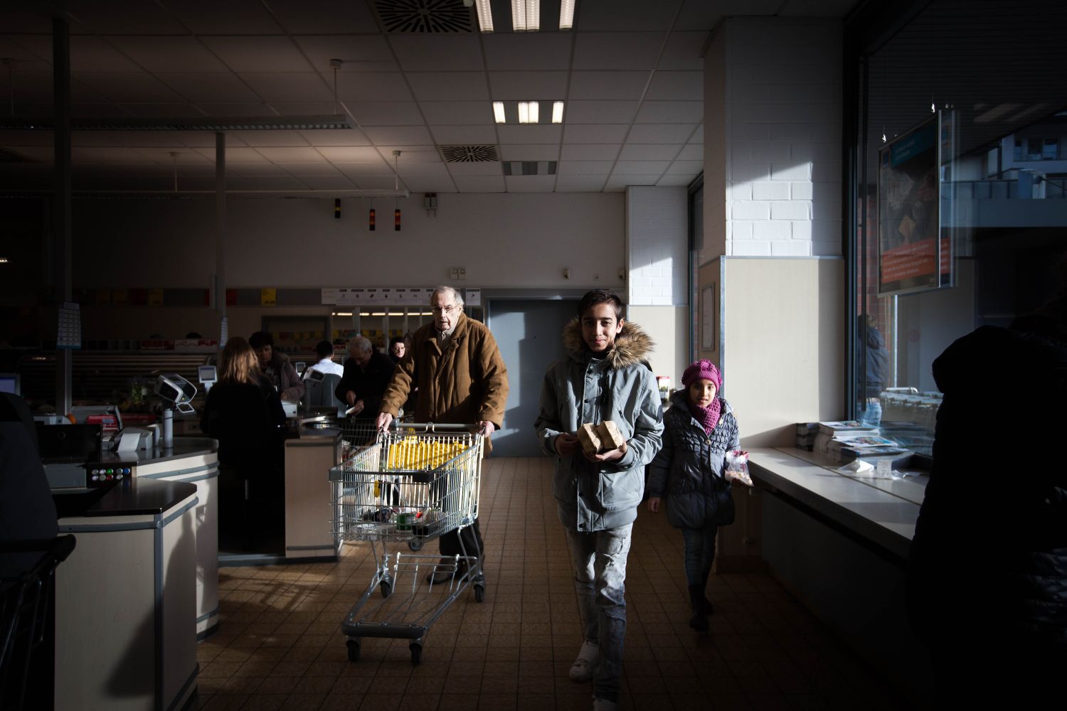 Milad and Mahya at the Aldi Süd discount supermarket in Düsseldorf. The Ahkabyars often shop as far as forty minutes away in order to save money on produce. Image by Diana Markosian. Germany, 2017.