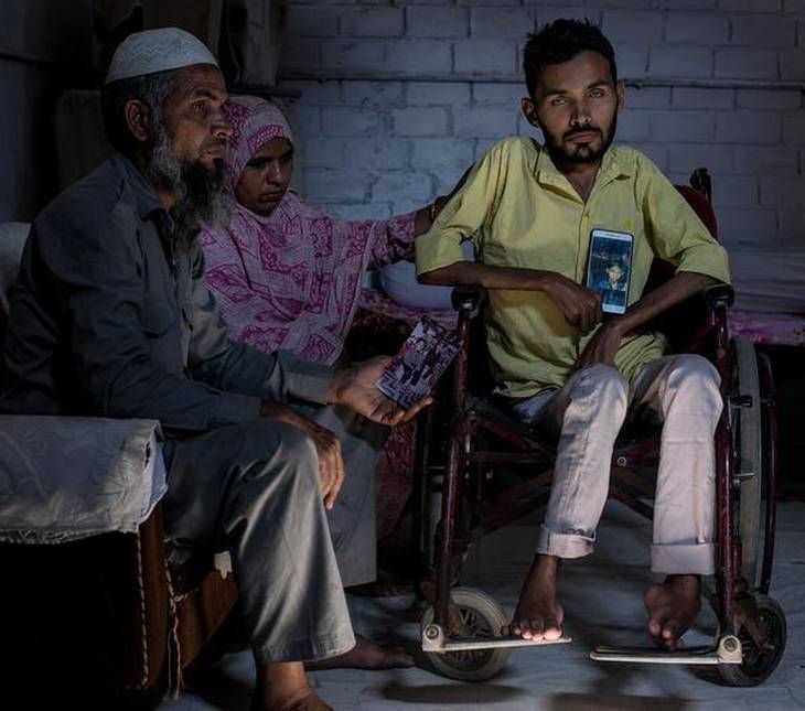 Brothers in distress: Umar Khan, 24, with his parents shows photos of his older brother Azhar who died last year. Azhar had muscular dystrophy as is Umar. Umar knows he will meet Azhar's fate soon. Image by Rohit Jain. India, 2018. 
