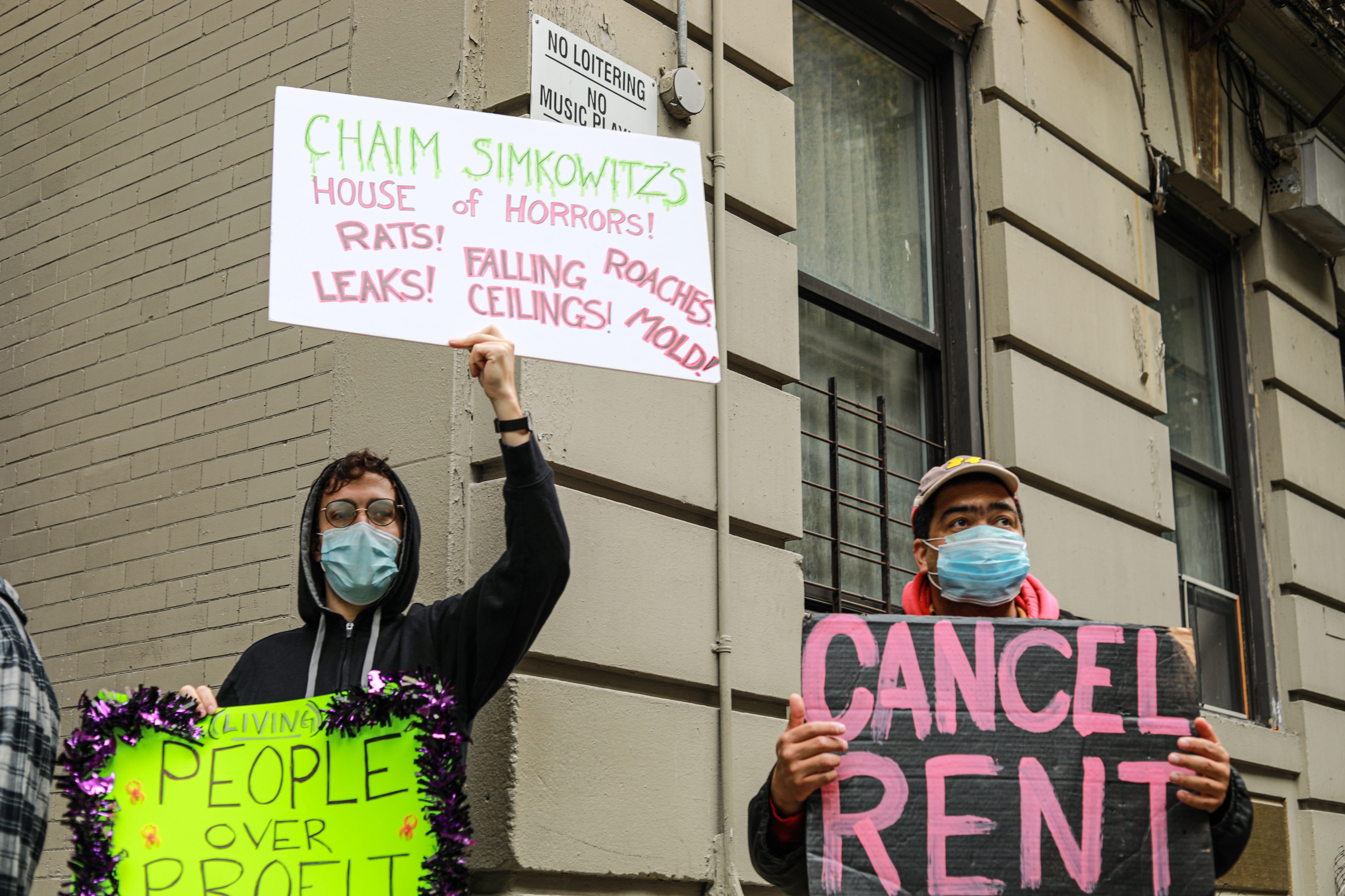 A renter and housing organizer stand in front of an apartment building to advocate for the cancellation of rent. Image by Kayla Hui. United States, 2020.