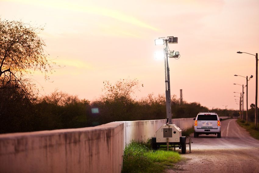 At dusk, Border Patrol agents place mobile floodlights along the levee-fence in Hidalgo County. Image by Callie Richmond. United States.