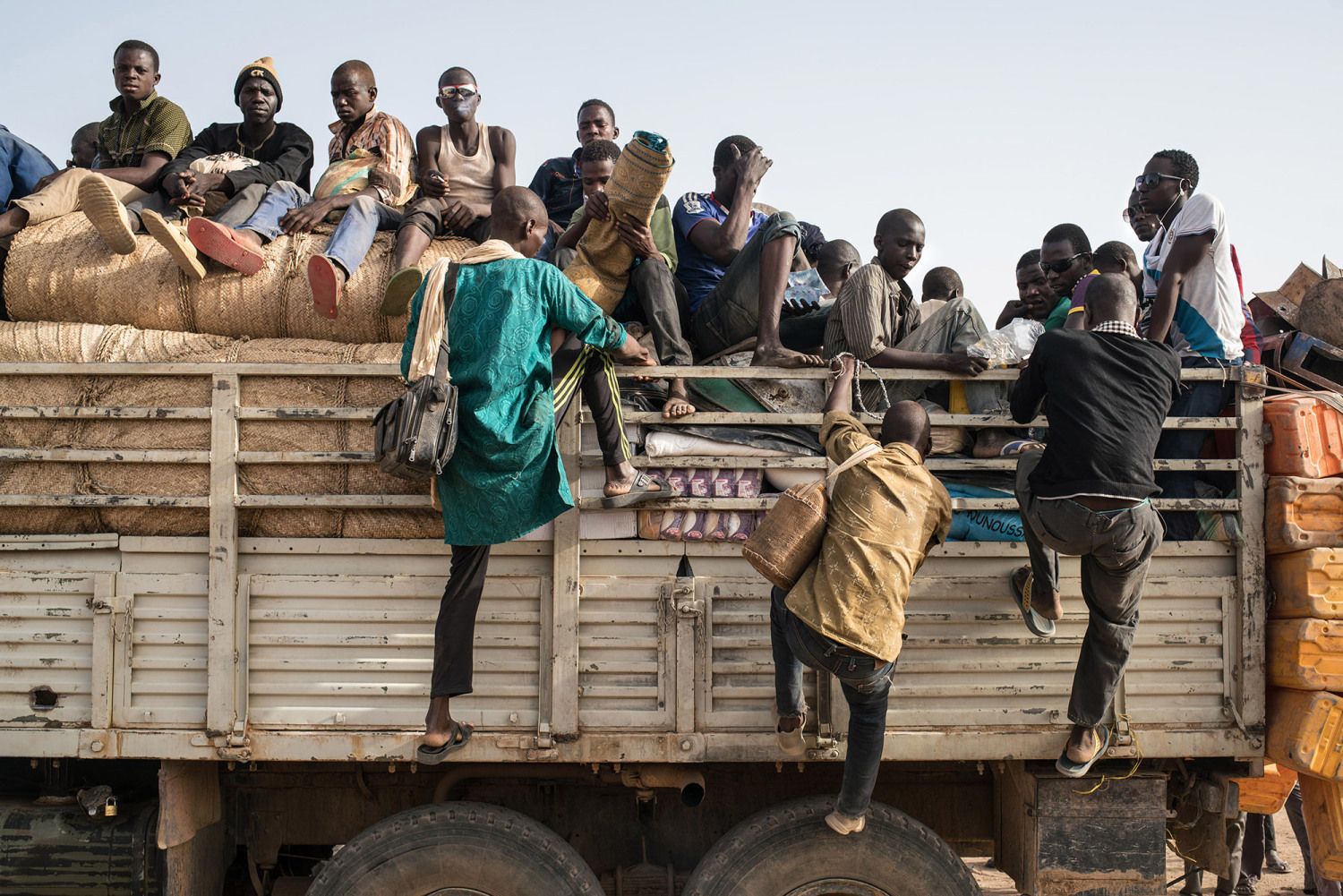 Migrant laborers climb onto the back of a truck bound for gold mines in the far north of the country. Image by Nichole Sobecki. Niger, 2017.
