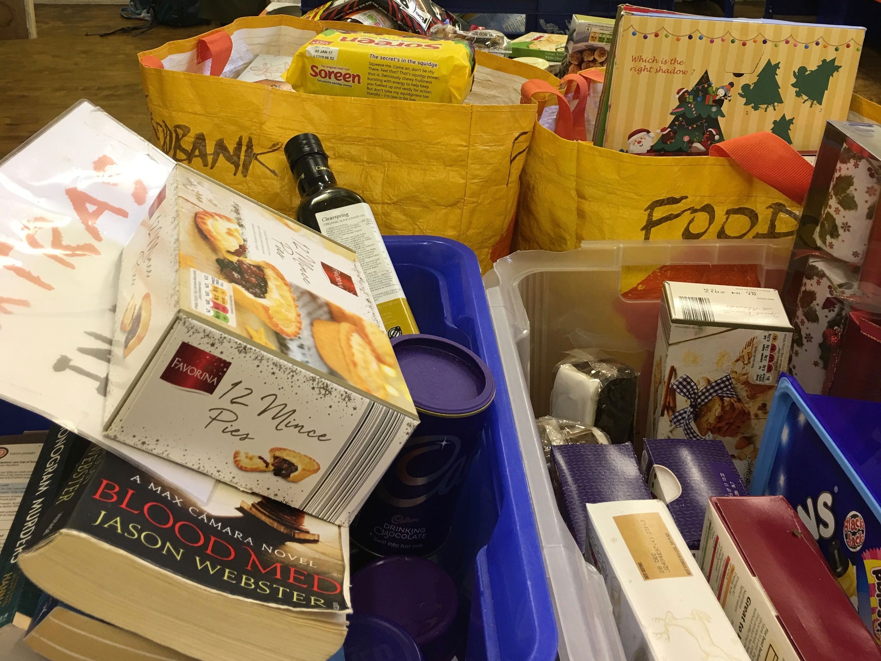 A box of miscellaneous items, including mince pies, books, Christmas crackers and biscuits. Donations are high during the holiday season, though the Food Bank urges volunteers to donate all year round. Image by Caitlin Bawn. England, 2016.
