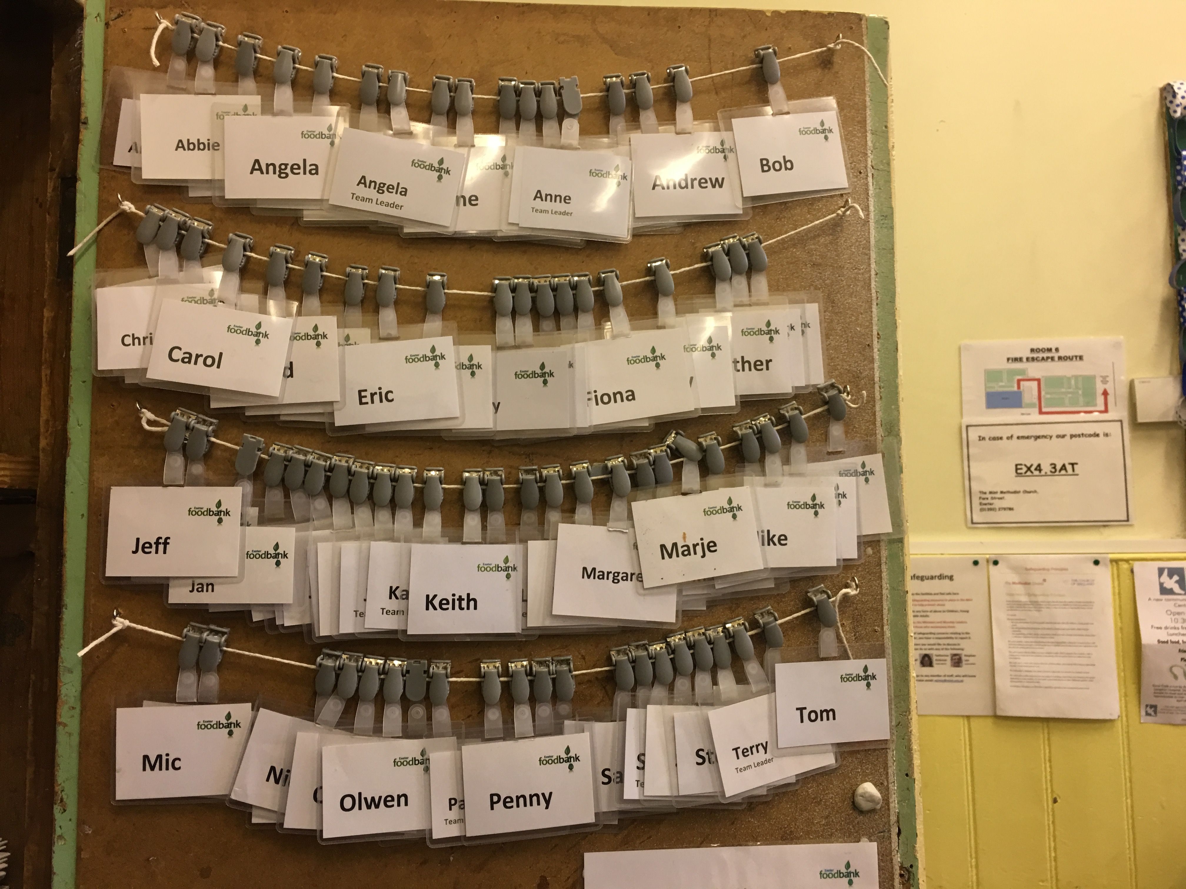 Name tags for Food Bank volunteers line the inside of a cupboard door. The Food Bank has 120 volunteers helping with the various aspects of their operation. Image by Caitlin Bawn. England, 2016.