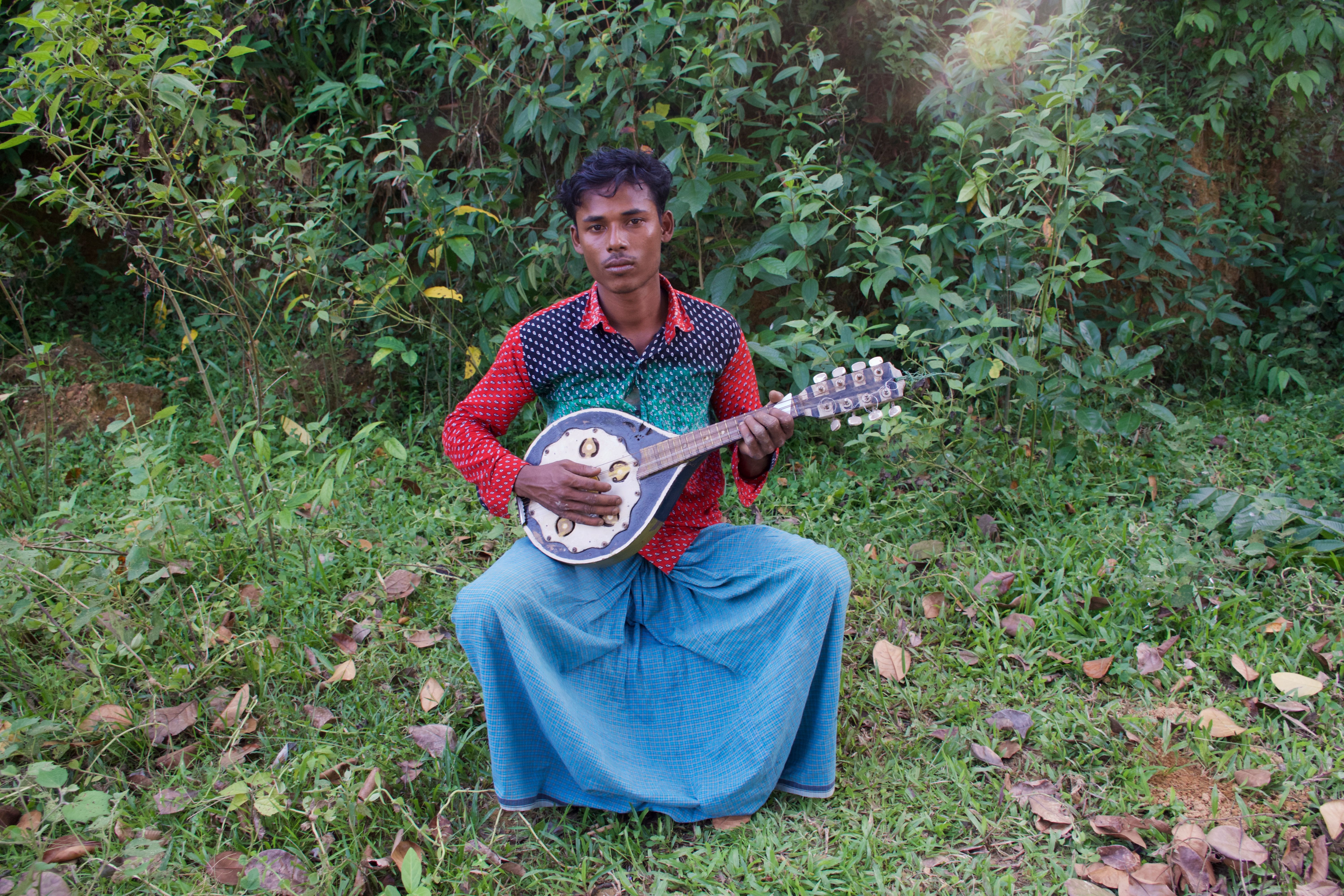 Rohingya musician in Bangladesh holds his mandolin.