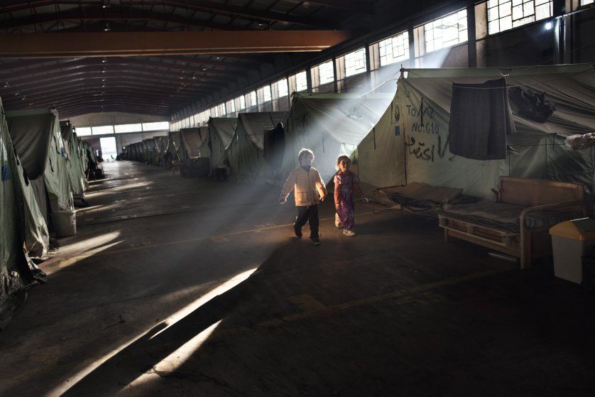 Syrian refugee children run through smoke emitted from fires lit by refugees trying to stay warm at the Oreokastro camp, where many refugees have already been moved to hotels. Image by Lynsey Addario. Greece, 2017.
