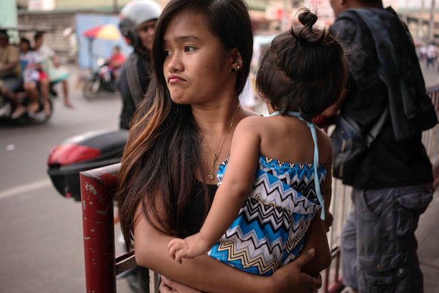 Jazmine Durana walks with her daughter Hazel in Navotas City, north of Manila, Philippines. Durana’s partner was killed a year ago by masked men. Image by Martin San Diego. Philippines, 2017.