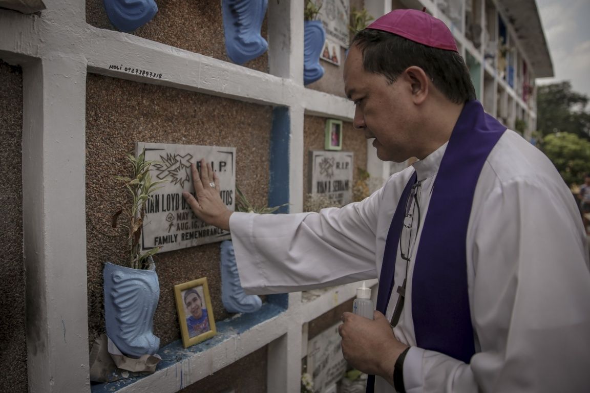Bishop Pablo "Ambo" David prays over the tomb of Kian Loyd Delos Santos in La Loma Cemetary, Caloocan, Manila. Image by Eloisa Lopez. Philippines, 2018. 