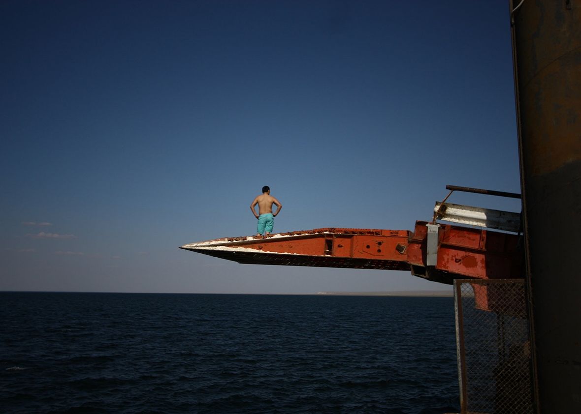A man prepares to dive off a pier into the Caspian Sea in Sarytas, Kazakhstan, next to the spot where Russian geographers have determined is the true Europe–Asia border. Image by Joshua Kucera. Kazakhstan, 2016.