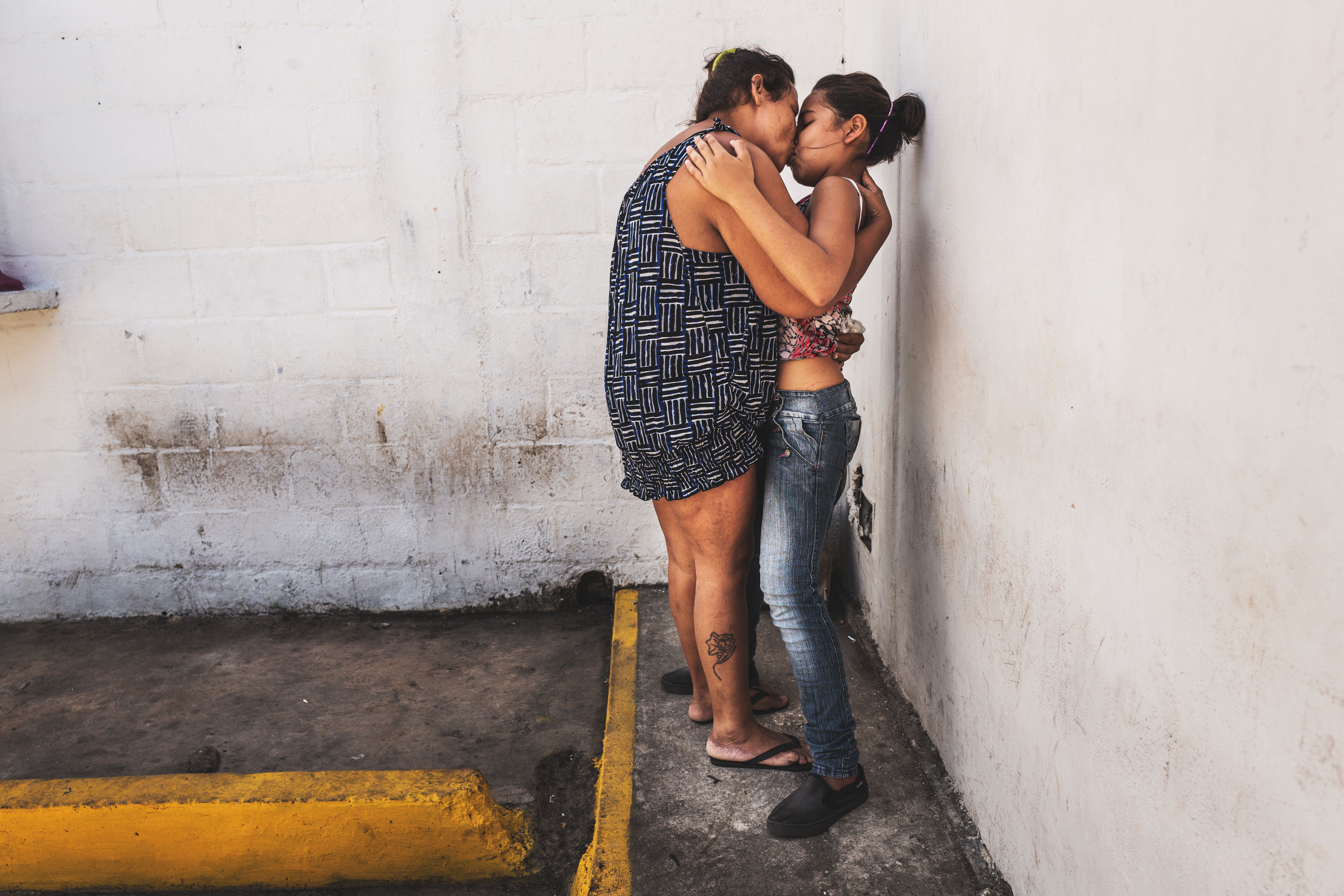 POLI-VALENCIA, CARABOBO - March 2018. Maria (on the left) kisses her daughter on visitation hours. She is 35 years old and is charged with robbery. She goes to therapy three times a week. While the beginning of the trials keep on being delayed, the condition of these women inside this precinct in the center of Valencia, a city on north-center of the country, has improved slightly between 2017 and 2018. They are now permitted to have a cellphone, hairdressing utensils and a 3hour recreation time outside their cell. Conjugal visitations are not allowed to female detainees, although one of them got pregnant while being inside the center with another male detainee; they had intercourse in the reception offifice. Image by Ana María Arévalo. Venezuela, 2018.