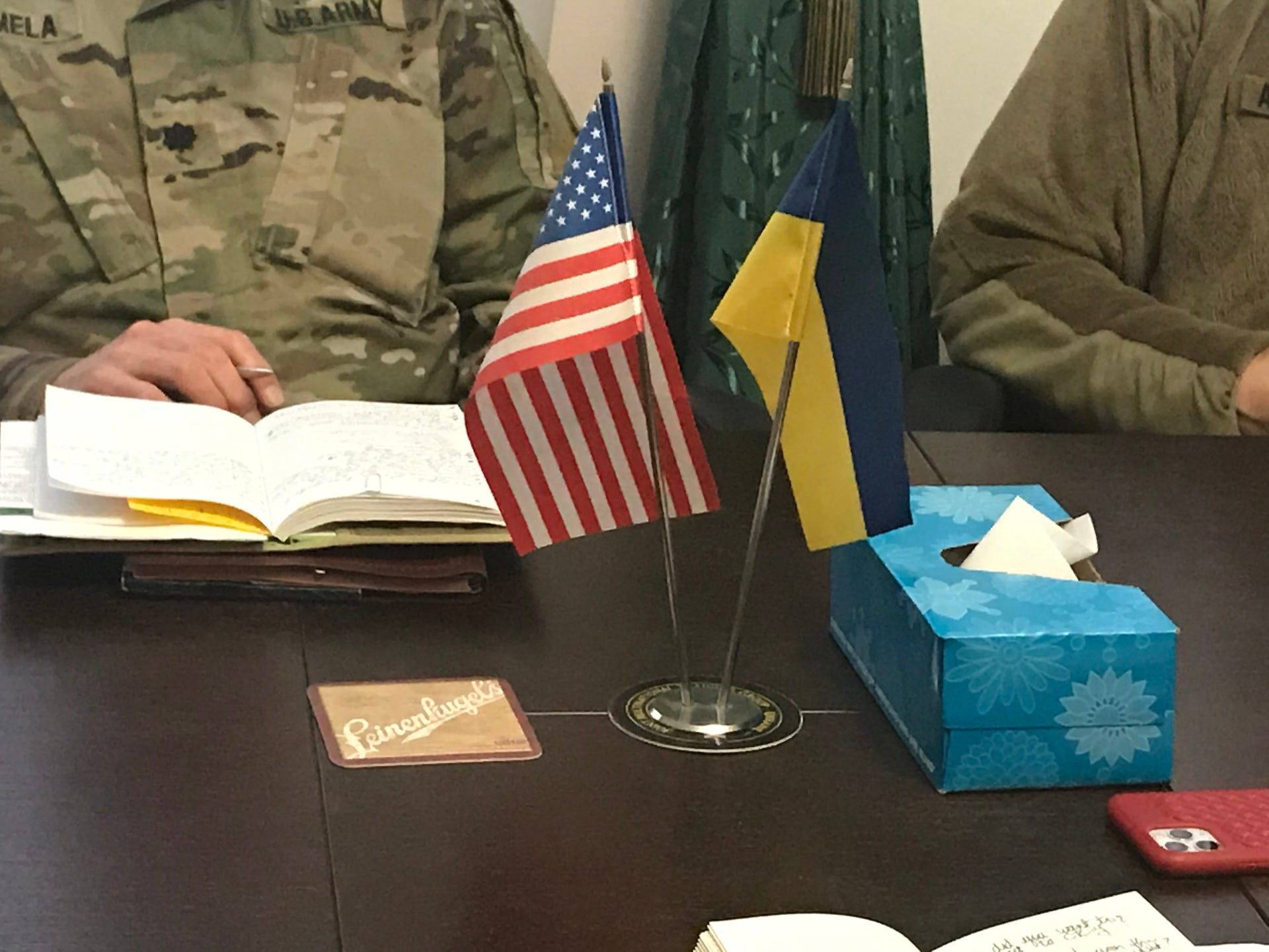 American and Ukrainan flags sit on a conference table in the office of Col. John Oakley and Command Sgt. Maj. Joel Rothbauer at a combat training facility in Ukraine. Rothbauer lives in Chippewa Falls and brought the Leinenkugel's coasters from home. Image by Meg Jones / Milwaukee Journal Sentinel. Ukraine, 2020.