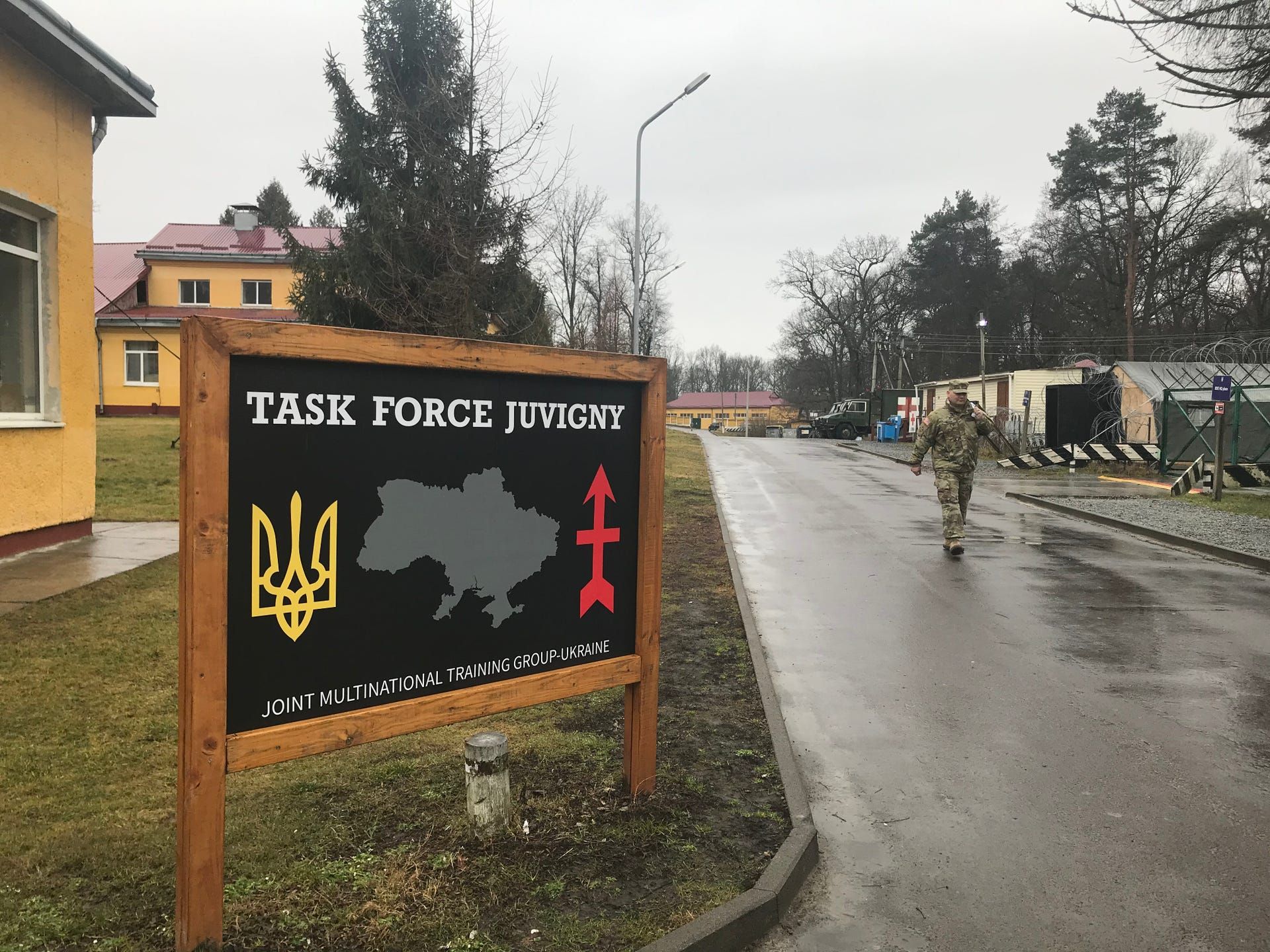 Chief Warrant Officer 3 Nathan Weier walks past a sign for Task Force Juvigny, the Wisconsin National Guard unit deployed to a combat training center in western Ukraine. Image by Meg Jones / Milwaukee Journal Sentinel. Ukraine, 2020.