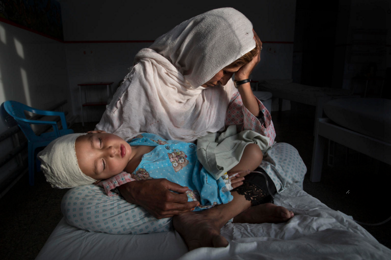 Najiba holds her nephew, Shabir, who was injured from the same bomb blast that killed his sister. Najiba watched over the children while Shabir’s mother buried her daughter. Image by Paula Bronstein. Afghanistan, 2016. 
