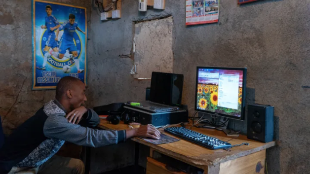 Caleb Yongo, a resident of the Gatwekera neighborhood in Kibera, Nairobi. Caleb runs a business from his house doing printing, photocopying, and typing. He uses an illegal power connection as that is the only power available for him. Image by Peter DiCampo. Kenya, 2018.
