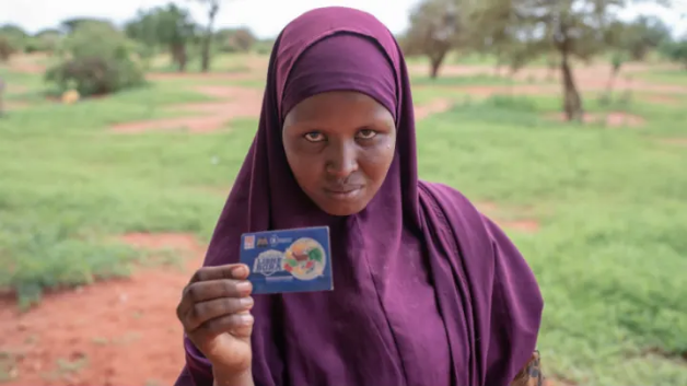 Farhiya Shimay Garore, 24, in Boji-Yeri, Wajir County. A resident of Boji-Yeri, she was registered into the World Food Programme project that targeted malnourished mothers and children under five. She was to receive cash transfers amounting to $120 over a period of three months. By the time the period ended she had only received $40. Image by Peter DiCampo. Kenya, 2019.