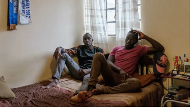 Collince Onyango, 27, left, and his brother Raphael Oduor, 24, right, both university students, in their home in Kibera, Nairobi, Kenya. Collince and his brother rent a single room from a resident who was lucky to move into the new houses that were built under the Kenya Slum Upgrading Project. Image by Peter DiCampo. 2018.