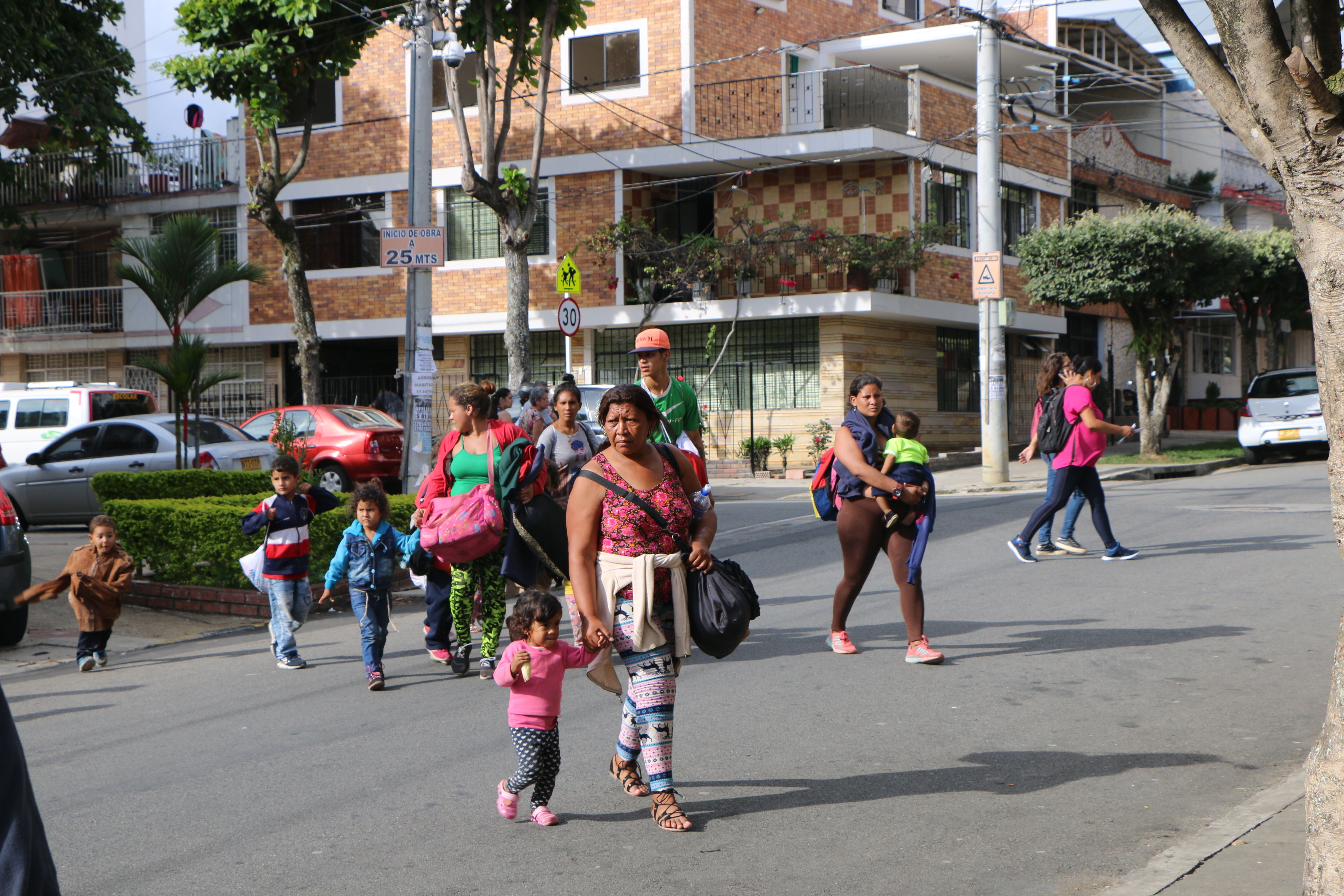 Venezuelan parents and children arrive at Fundación entre dos Tierras, one of the organizations providing aid to arriving migrants, in Bucaramanga, Colombia. At Fundación entre dos Tierras, volunteers serve migrants hot food and provide donations of clothing and other supplies. Image by Patrick Ammerman. Colombia, 2019.