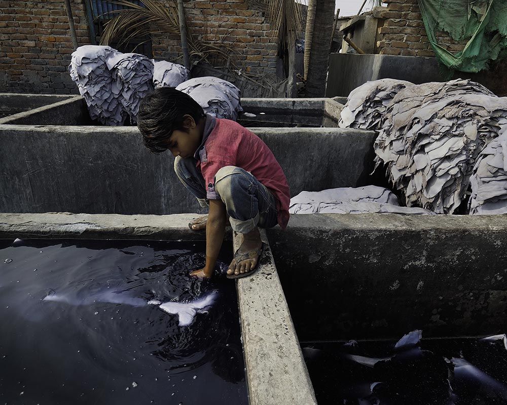 Very young children can often be found playing and working around deep, open vats of tanning chemicals. This child stirs hides soaking in a chemical bath. Image by Larry C. Price. Bangladesh, 2016.