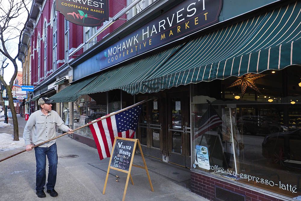 The Mohawk Harvest Cooperative Market is among the first businesses on Gloversville’s Main Street to receive grant funding under the city’s redevelopment program. General Manager Sean Munk places the flag that flies outside the market. Image by Larry C. Price. United States, 2016.