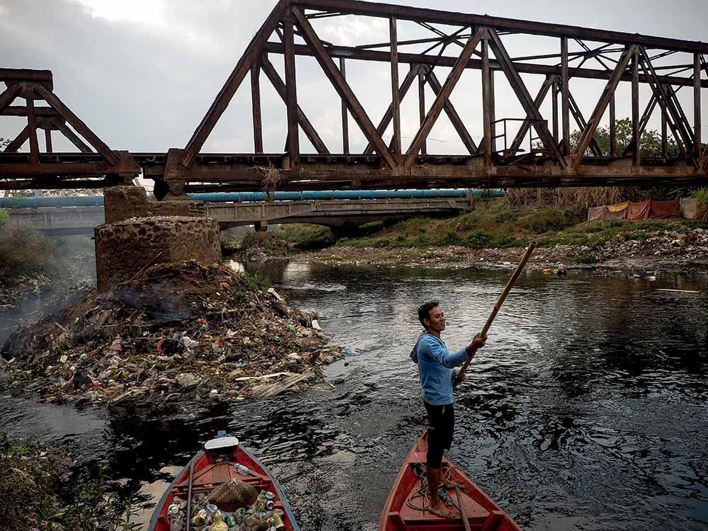 Heaps of trash smolder at the base of a railroad trestle near Cigado, Indonesia. The Citarum River, one of the world’s most polluted, flows from the mountains to the Java Sea. Image by Larry C. Price. Indonesia, 2016.
