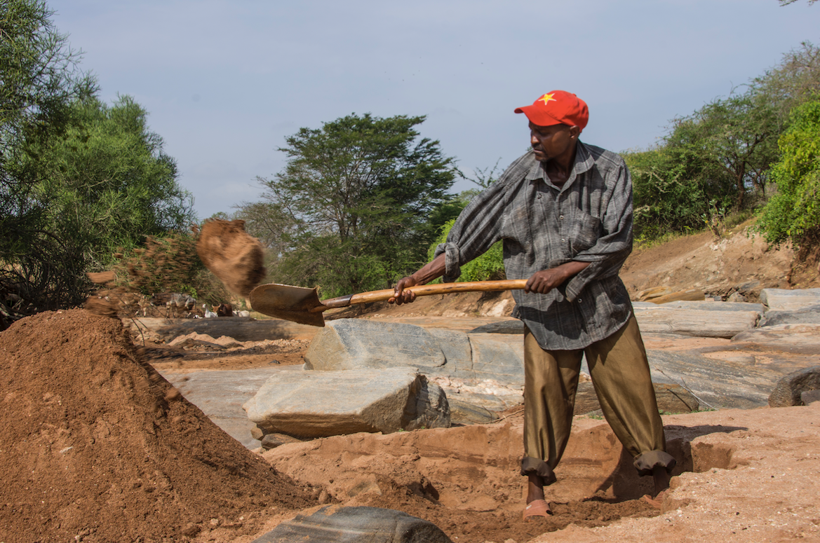 A man harvests sand in Makueni. Sand mining has drastically changed the ecosystem across the county. Image by Rachel Reed/Harriet Constable. Kenya, 2015.