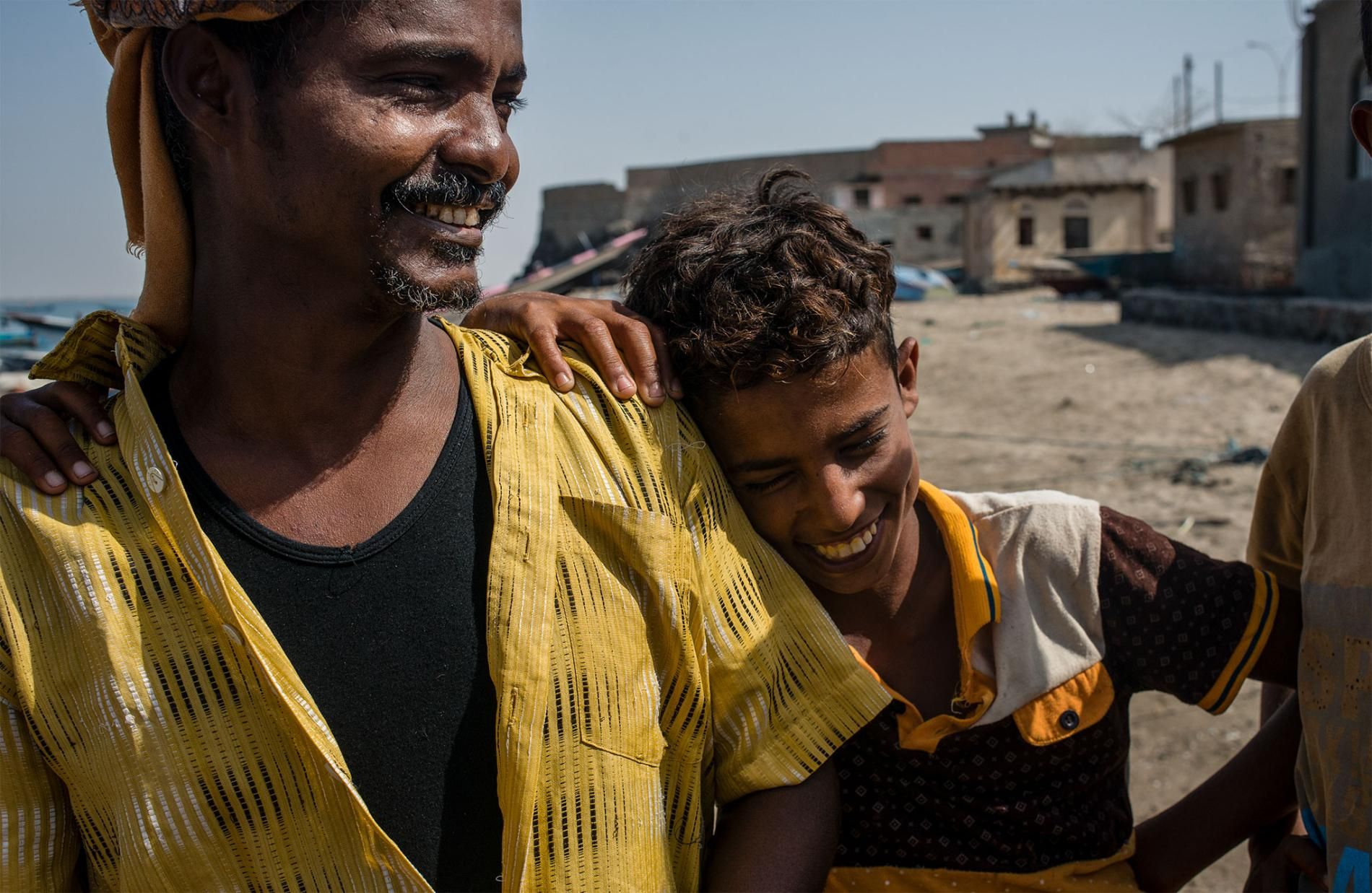 Shafai Saleh Hadi (left) laughs with local boys on the shore of Bir Fuqum. As a first-generation fisherman, he sees the job as a better route for his sons than attending school, since employment is incredibly scarce in Yemen. Image by Alex Potter. Yemen, 2018.