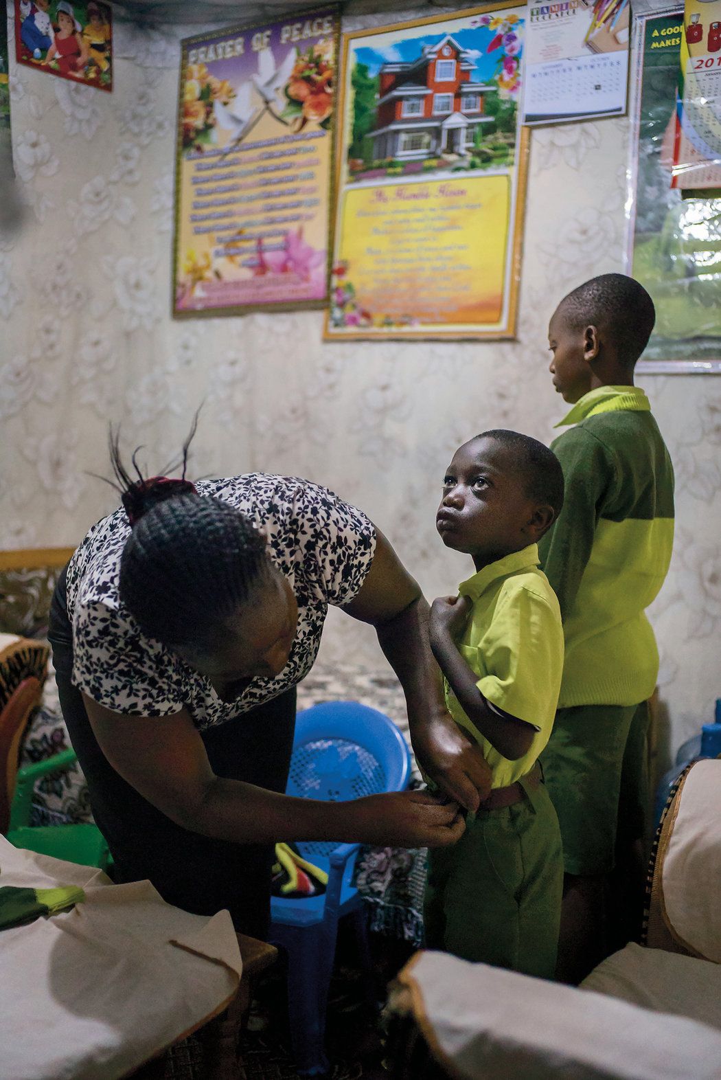 Elizabeth Mumo prepares her sons—Samuel, center, and Joshua—for school at the Kiserian Bridge school. She says she has high hopes for Joshua: ‘‘I can see Oxford.’’ Image by Diana Zeyneb Alhindawi for The New York Times. Kenya, 2017.
