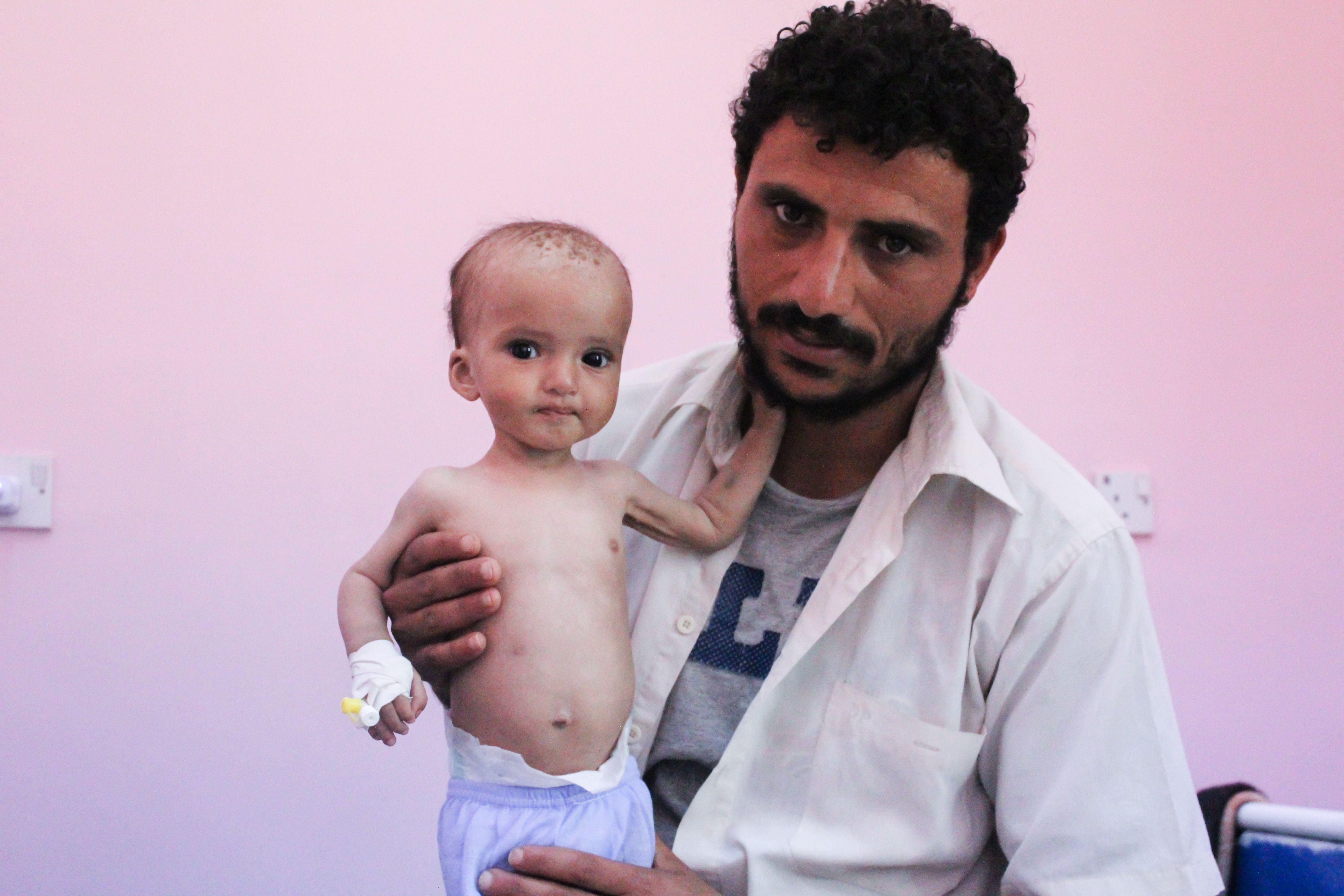 Burhan Nasser holds his nine-month old son, Shaker, at the only therapeutic feeding centre for children suffering from severe acute malnutrition in Yemen's city of Aden. Image by Iona Craig. Yemen, 2017.