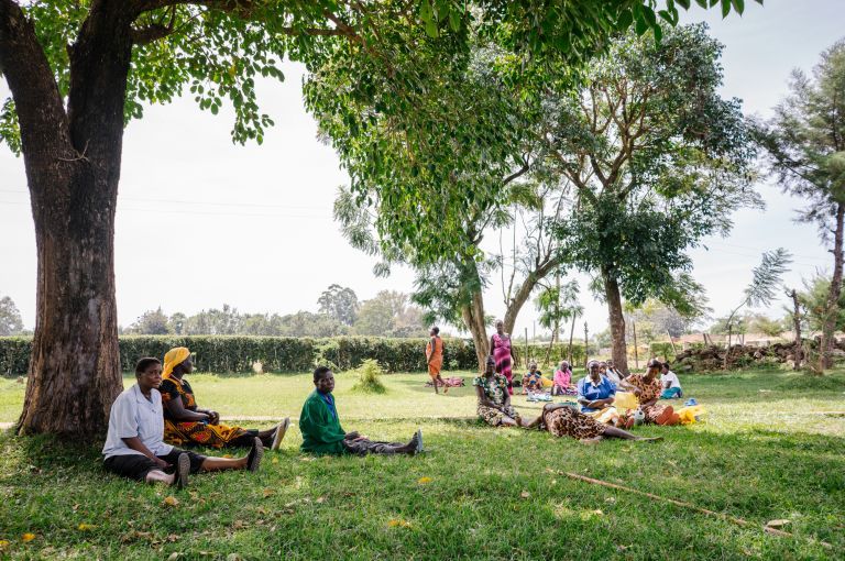 Women sit outside the Bumula Health Center and wait for their turn at maternity services. Image by Jake Naughton. Kenya, 2015.
