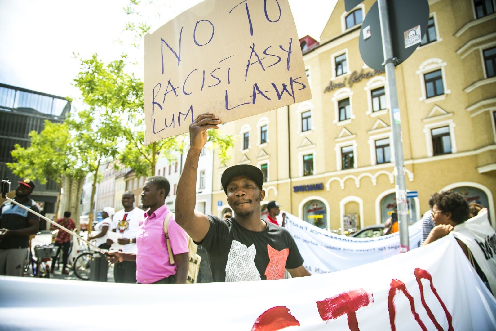 A Nigerian asylum seeker holds up a sign during a protest of Anker centers in Bavaria, Germany. Image by Angelica Ekeke. Germany, 2019.