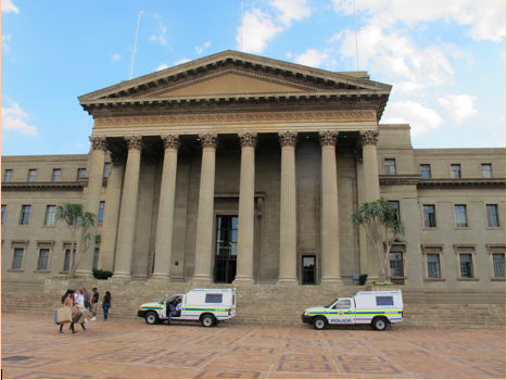 The Great Hall rests at the head of the central hub of the Braamfontein campus at the University of Witwatersrand. Many of the most remembered protests have taken place at university centers, and the Great Hall is no exception. Two police vehicles wait along with four others not pictured outside during the registration period. Image by Lorraine Pettit. South Africa, 2016.
