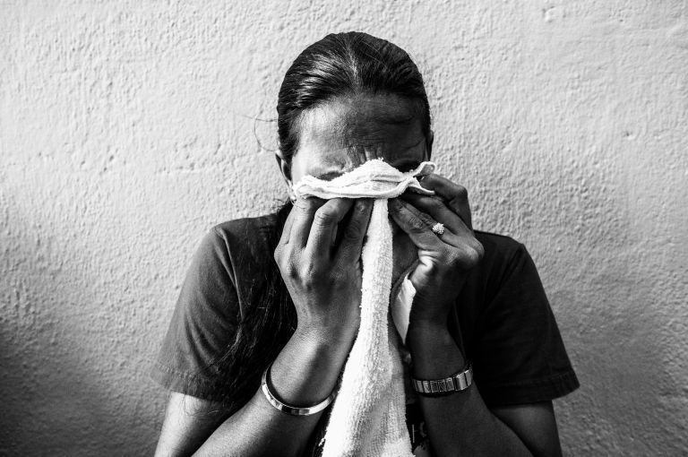 Karamjit, a 45-year-old Indian migrant, wept as she she shared her story with other runaways in the shelter. She has been staying in the shelter for three months. She told the photographer that she was physically abused by her employer but that she wants to continue working in Singapore. Image by Xyza Bacani. Singapore, 2016.