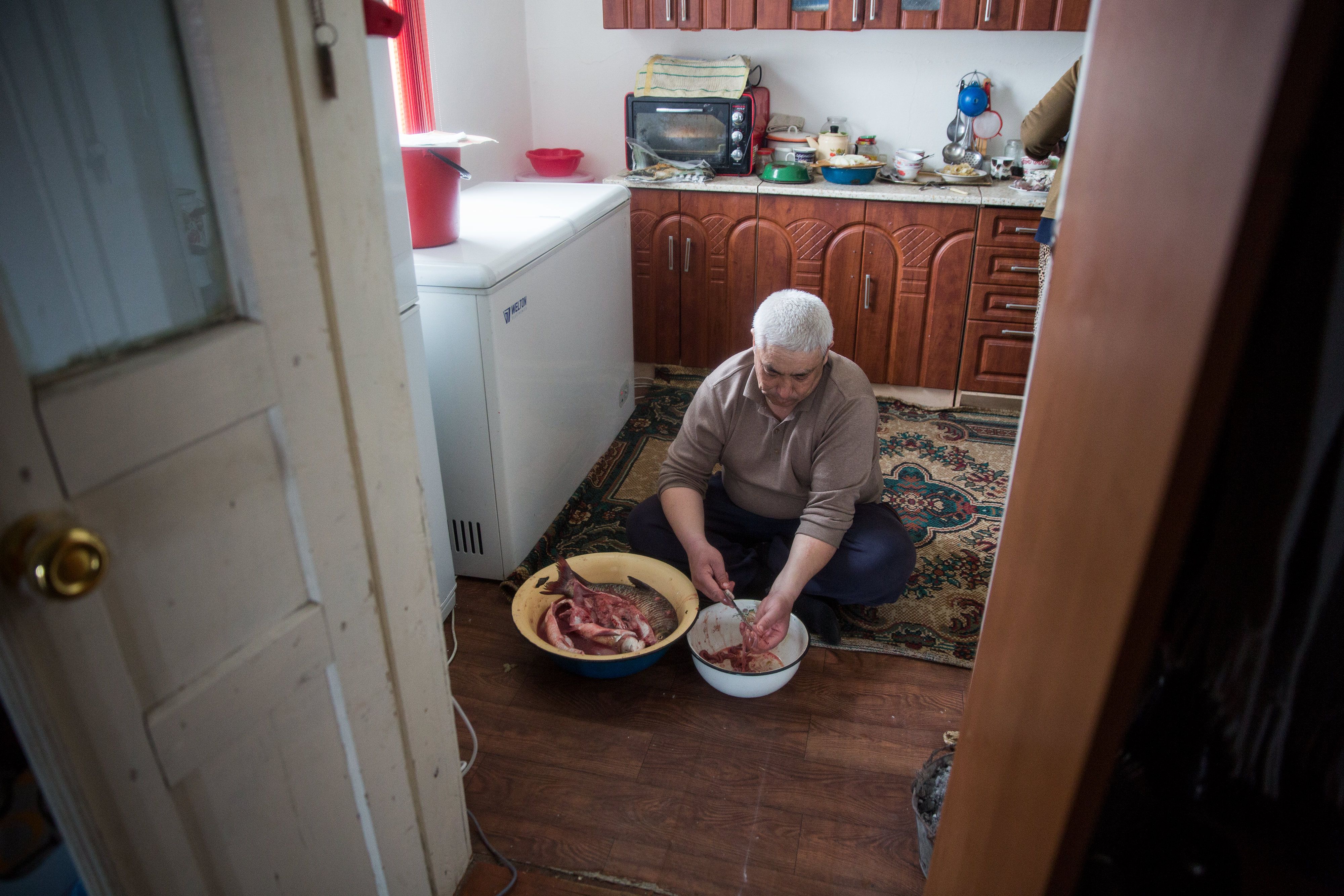 Kiderbai Ibragimov, 45, prepares a fish meal at home in Tastubek. Image by Taylor Weidman. Kazakhstan, 2017.