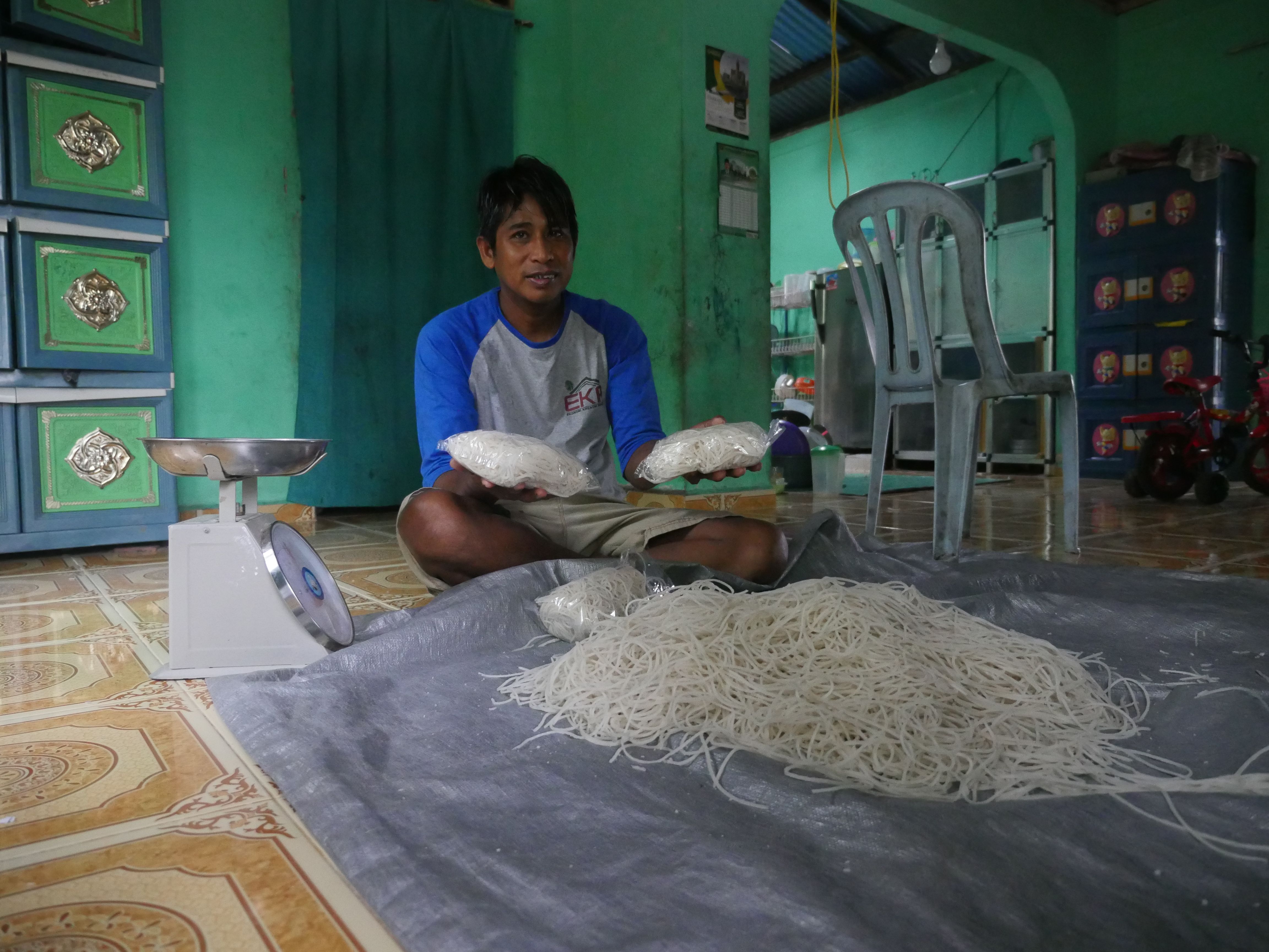 Abdul Manan makes sago noodles with a small pasta maker and packs them for retail sale in plastic bags. He sells about one ton of pasta each month. Image by Daniel Grossman. Indonesia, 2019.