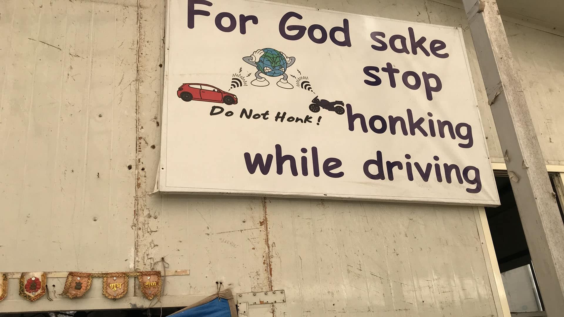 An anti-honking sign hangs on the wall at the Earth Saviours Foundation just outside New Delhi. The foundation is active in caring for the homeless and several environmental causes, including noise pollution. Image by Chris Berdik. India, undated.