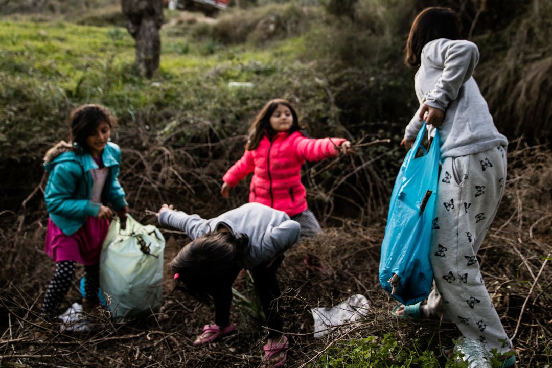 Asal, Ezin, and Damsa gather firewood in Moria on Lesbos, on January 4, 2020. Without electricity or proper shelter, the family relies on heat from open fire for temporary warmth. Image by Maranie Staab. Greece, 2020.