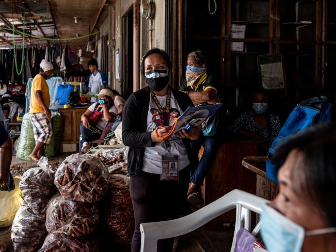 Filipina nurse April Abrias in a crowded vegetable market while checking on patients showing symptoms of Covid-19. Image by Xyza Cruz Bacani. Philippines, 2020.