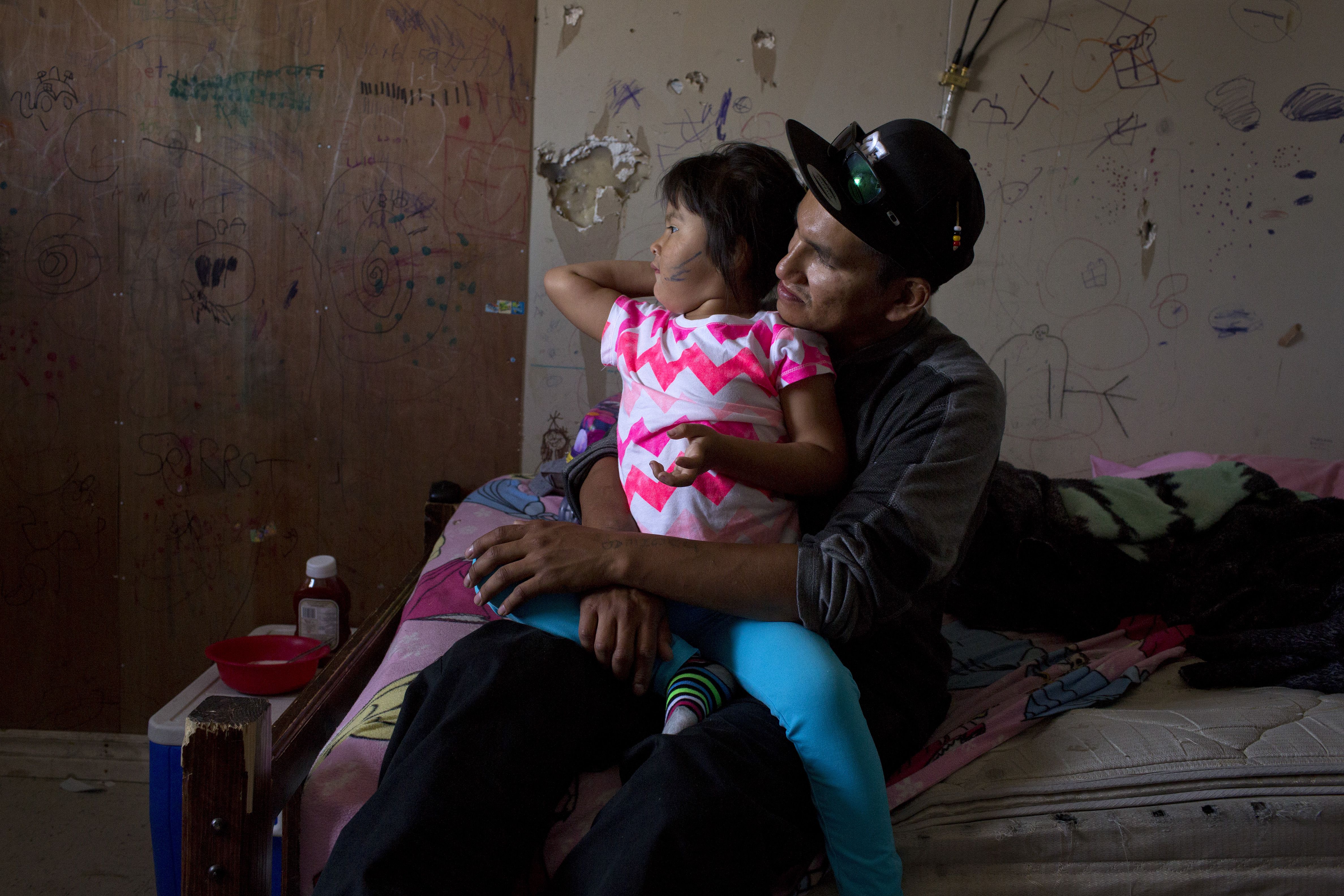 Sam Koosees sits in his bedroom with his three-year-old daughter Arianna. They share a three-bedroom trailer with ten other family members, a common situation in a community with a dire housing shortage. For Sam, a carpenter, life revolves around creating a better situation for his daughter. Despite a challenging past and the pitfalls of living in a remote, under-serviced First Nations community, he has goals and dreams for them both. While spending time with Sam, I became acutley aware of the stereotyped view of young First Nations men I was used to seeing in the media. I met several other caring fathers while I was there and cannot help but wonder how a stereotyped view of First Nations people in general exacerbates the issues they face. Image by David Maurice Smith. Canada, 2016.